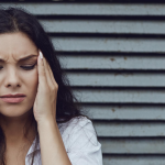 a woman in pain is holding her head with her eyes closed